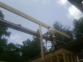 Carpenter setting a ridge beam over a new addition frame — Ice Dam Removal by Roofing Brothers in East Meadow