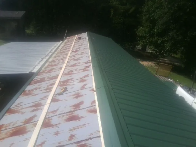 Old rusted panels beside newly installed green metal roofing — Wind Damage Roof Repair by Roofing Brothers in East Meadow