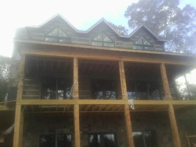 Dormers and porch framing on a large log home under construction — Roof Coating work by our crew in East Meadow