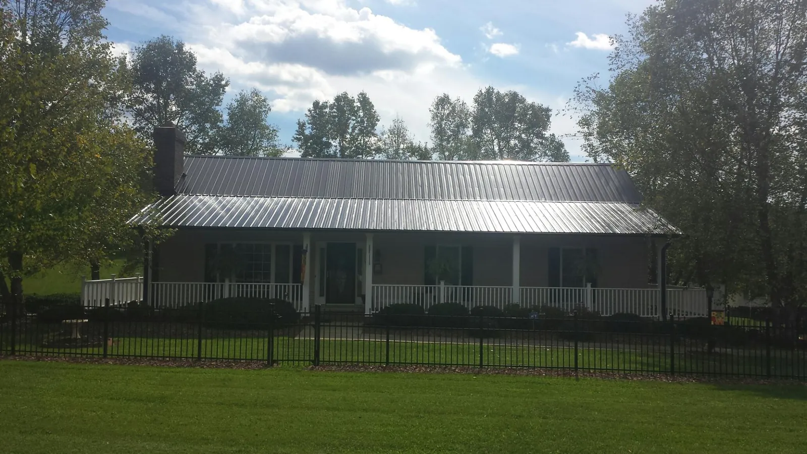 Gray metal roof on a brick ranch with a full width front porch — Gutter Guard Installation work by our crew in East Meadow