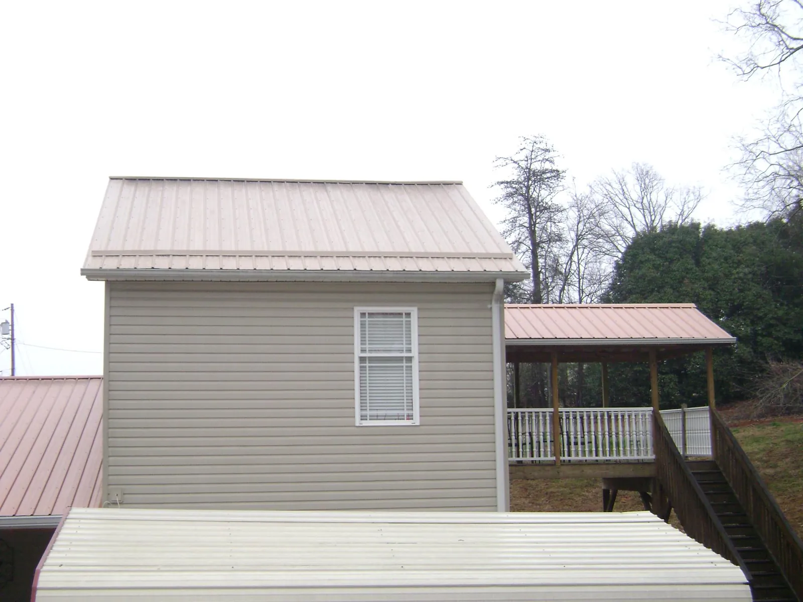 Tan metal roofs on a two story addition and attached porch, from a Roof Replacement job in East Meadow